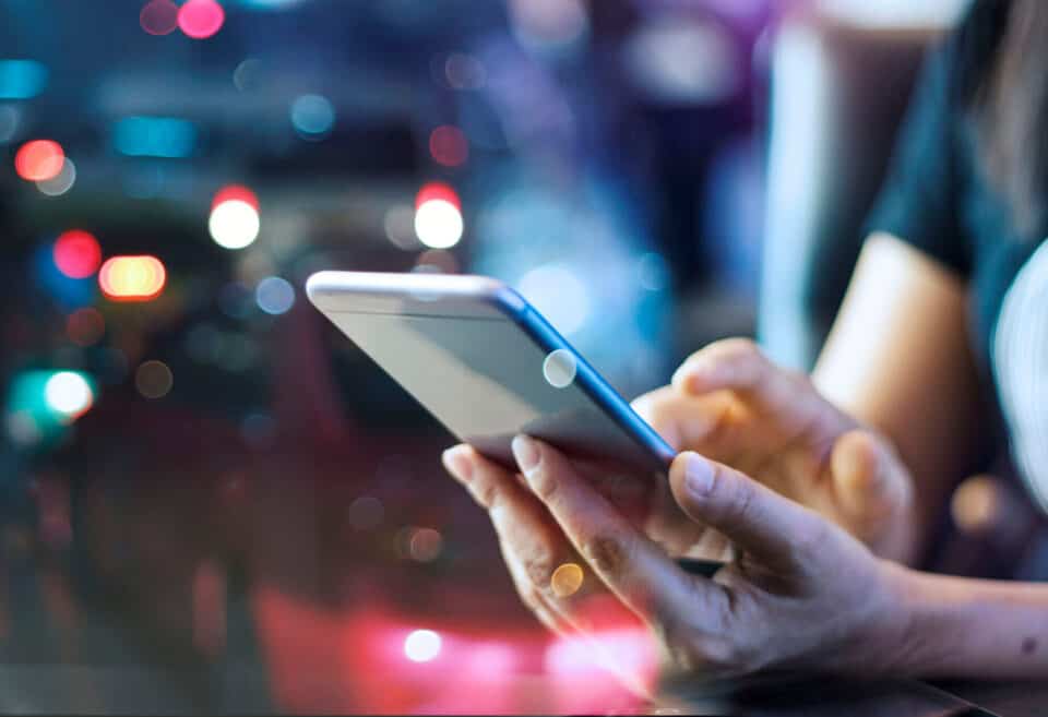 Woman using mobile smart phone in the night light colorful background